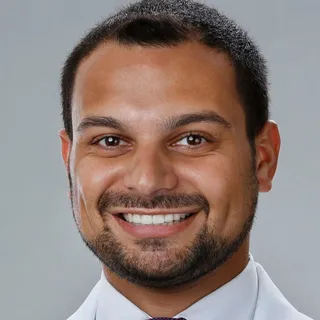A PWP coaching client and graduate student smiling in a white coat and tie.