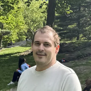 Nick T., a PWP coaching client, standing in a sunny city park.