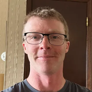 Tom O., a PWP coaching client, smiling in glasses at home.